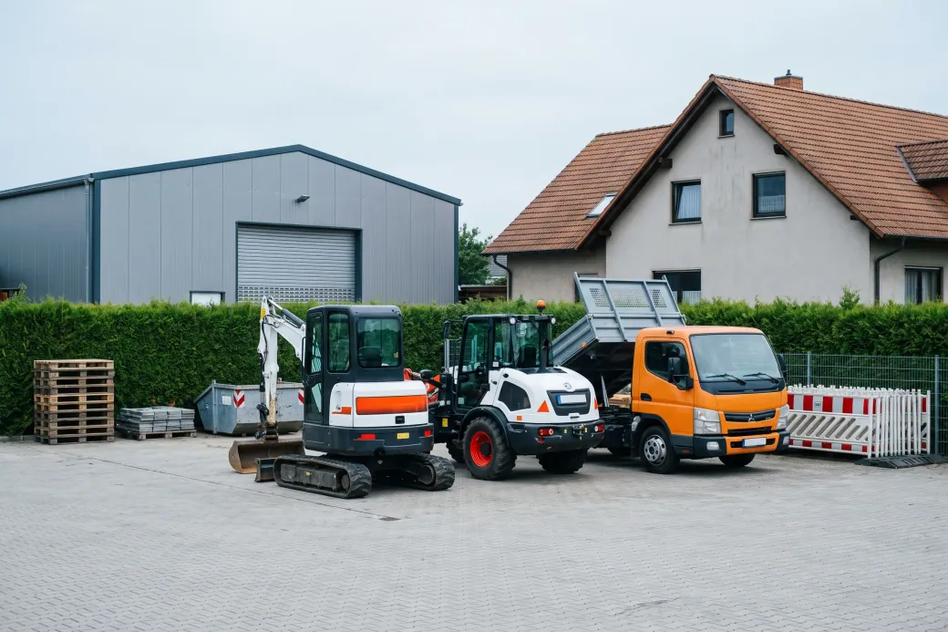 Minibagger, Radlader und Kipper nebeneinander auf dem Hof